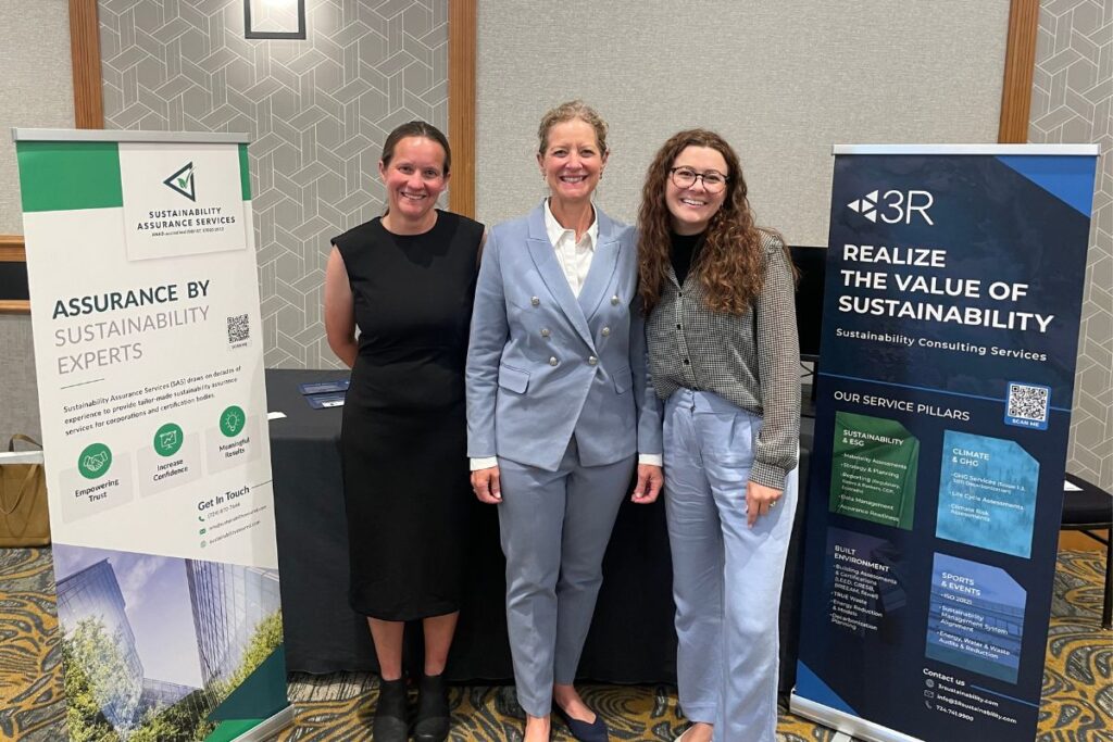 Gina, Jana, and Preston smiling in front of SAS and 3R banners